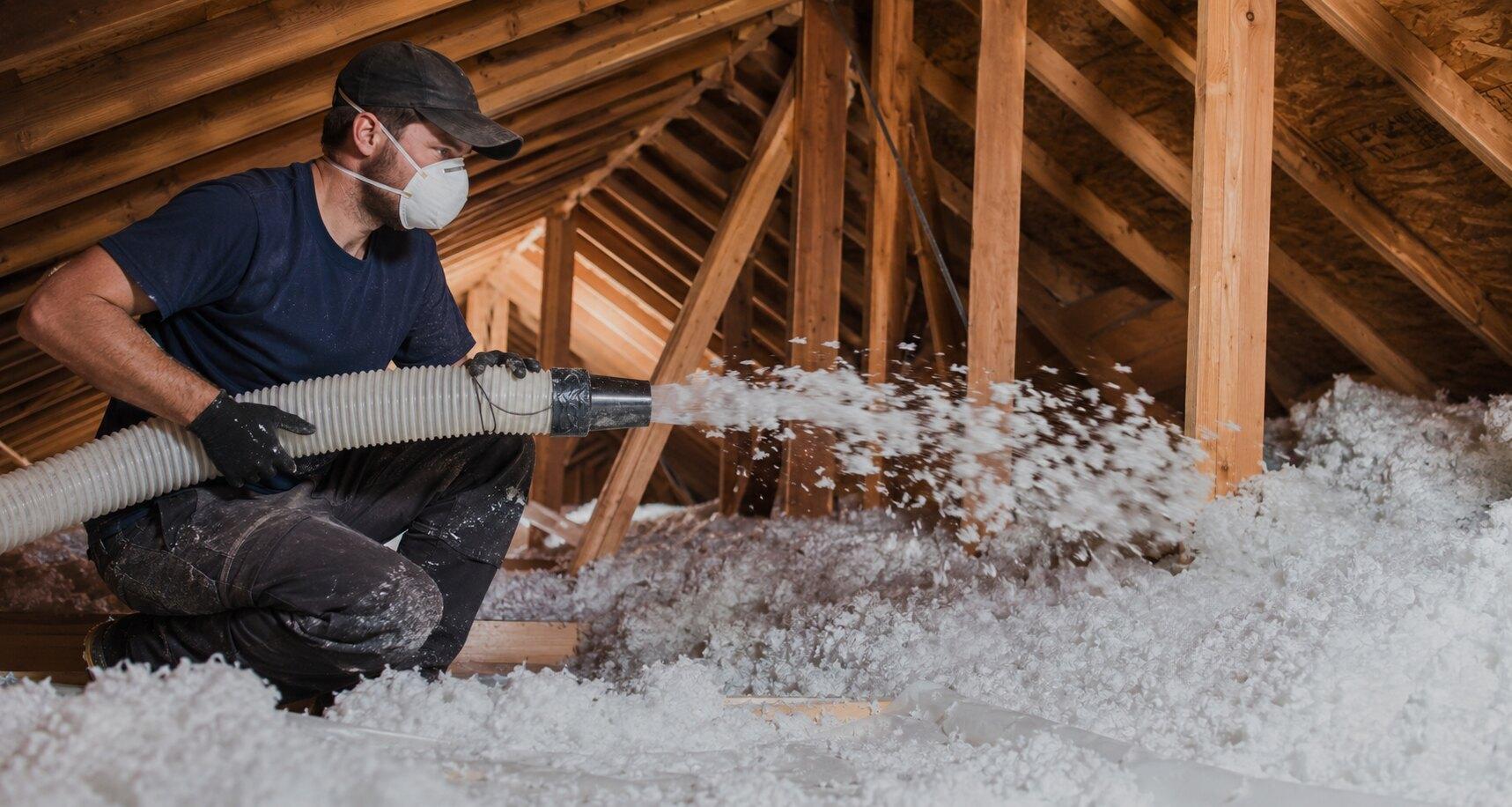 Insulation installer blowing loose-fill insulation across an attic floor in a Brevard County, FL home