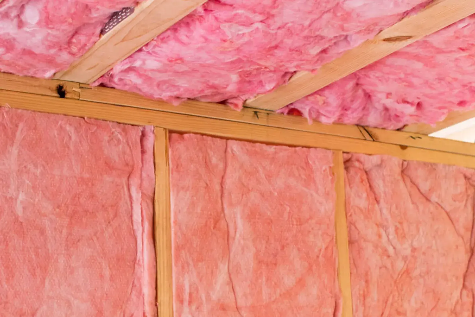 Pink fiberglass batt insulation installed between attic rafters