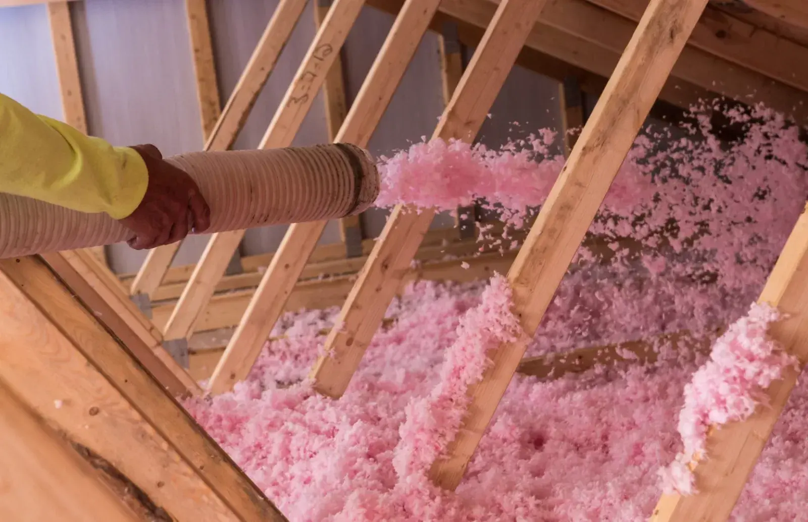 Pink blown-in fiberglass insulation filling a wood-frame attic in a Brevard County home