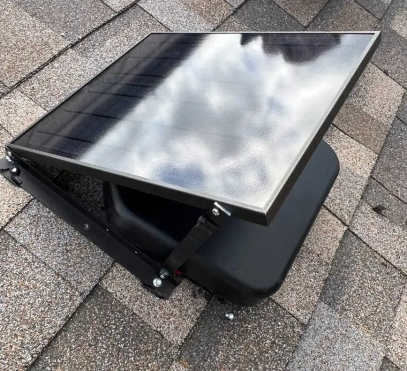 Solar-powered attic ventilation fan installed on a shingled roof